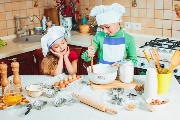 De gelukkige familie grappige jonge geitjes bereiden het deeg voor, bakken koekjes in de keuken