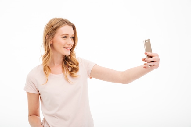 De gelukkige jonge vrouw neemt een selfie door mobiele telefoon.