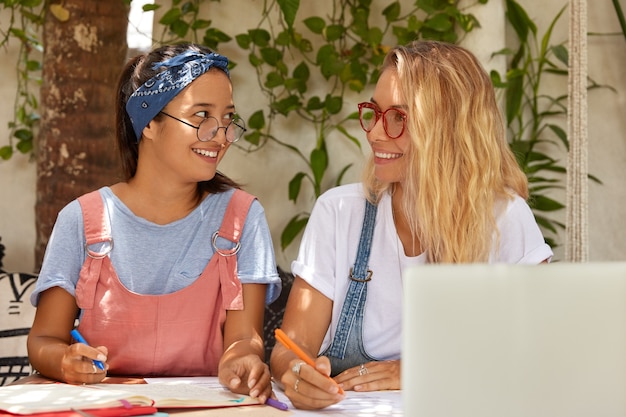 Gratis foto de gelukkige tevreden glimlachende tienerpennen van de studentengreep, bereiden zich voor op het schrijven van cursusdocument