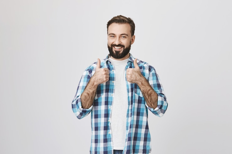 Gratis Foto de gelukkige tevreden mannelijke klant toont thumbs-up en glimlacht