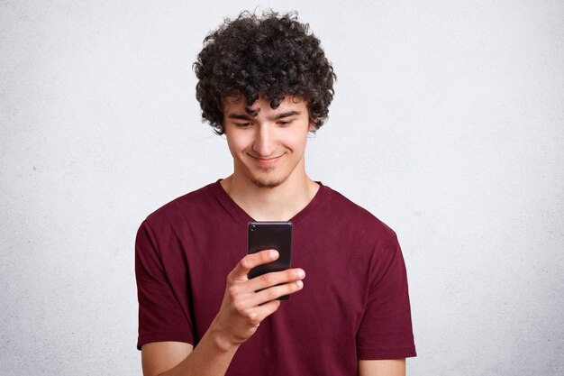 De gelukkige tiener kijkt graag op mobiele telefoon