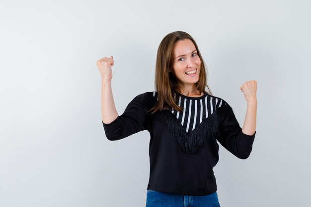 De gelukkige vrouw heft haar vuisten op witte achtergrond op