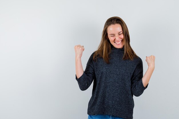 De gelukkige vrouw heft haar vuisten op witte achtergrond op