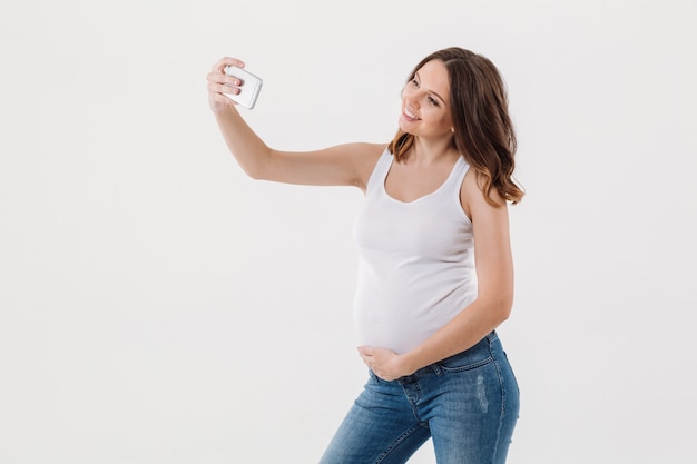 De gelukkige zwangere vrouw maakt selfie met haar buik