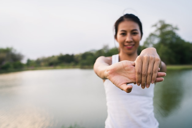 De gezonde jonge Aziatische agentvrouw warmt het lichaam op dat zich vóór oefening en yoga uitrekt