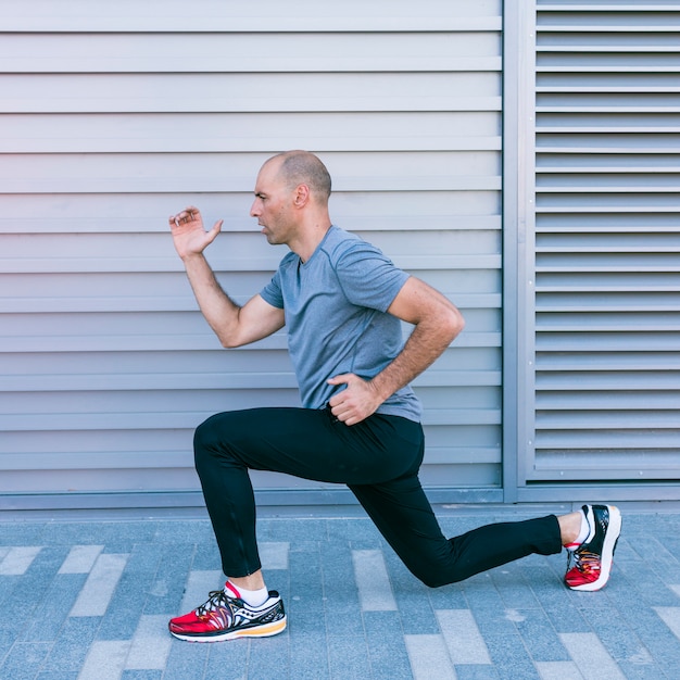 Gratis foto de gezonde mannelijke atleet die uitrekkende oefening doet begon alvorens te lopen