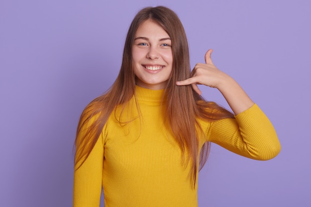 De glimlachende gelukkige vrouw kleedt het gele overhemd tonen roept me gebaar