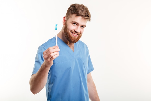 De glimlachende jonge mannelijke tandenborstel van de tandartsholding