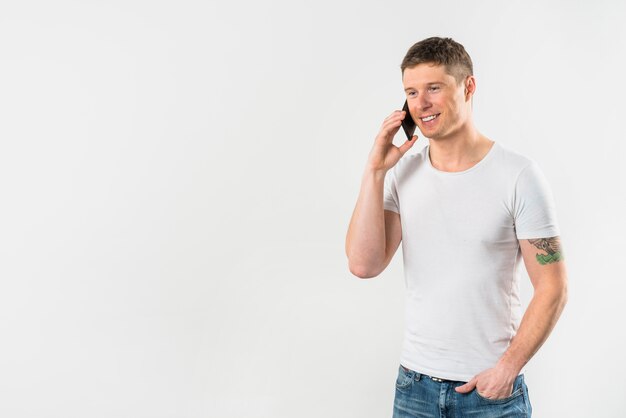 De glimlachende jonge mens die op mobiele telefoon met van hem spreken dient zak in