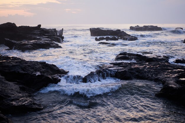 de golven van de oceaan breken tegen de rotsen. oceaan golven spatten bij zonsondergang.