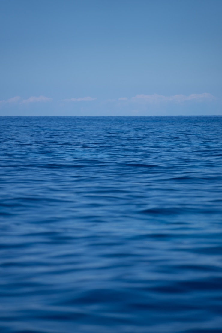 Gratis Foto de golven van de oceaan onder een heldere blauwe hemel