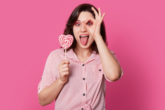 De grappige gelukkige jonge vrouw maakt ok gebaar