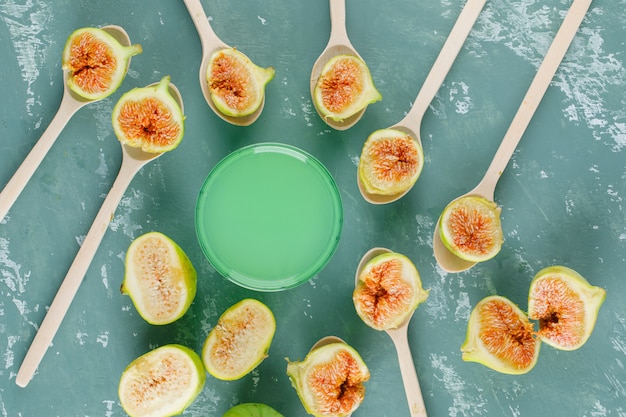 De groene vijgen met drank in houten lepels op vlakke pleistermuur, lagen.