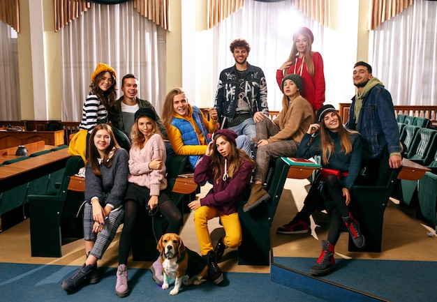 De groep van vrolijke gelukkig studenten zitten in een collegezaal voor de les