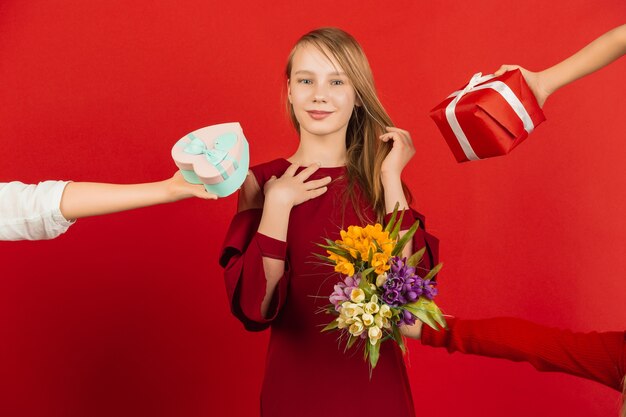 De grootste keuze. Valentijnsdagviering. Gelukkig, leuk Kaukasisch meisje dat op rode studioachtergrond wordt geïsoleerd. Concept van menselijke emoties, gezichtsuitdrukking, liefde, relaties, romantische vakanties.