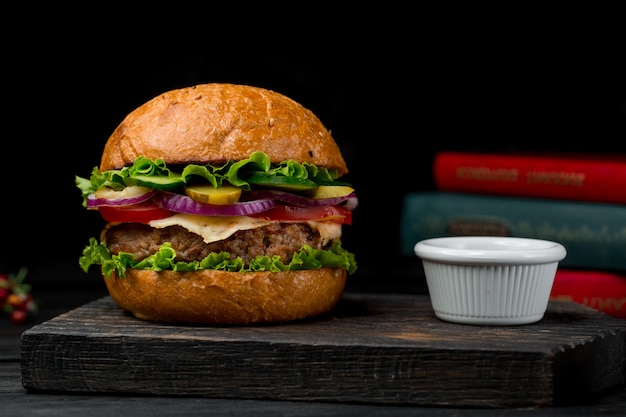 De hamburger van de rundvleescotlet met saus op een houten raad