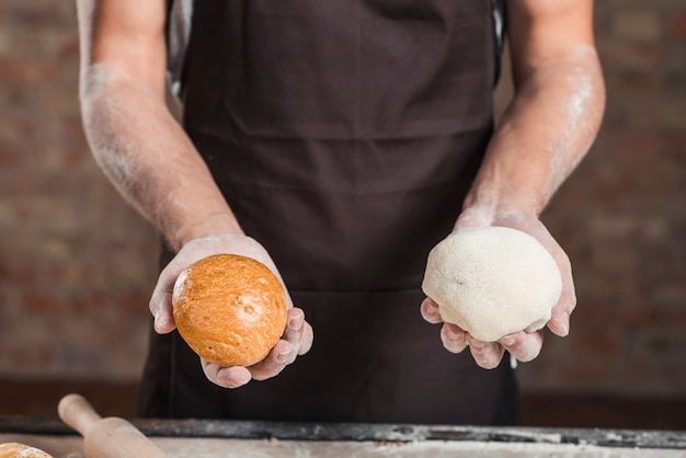 De hand die van Baker gebakken brood en deeg houdt