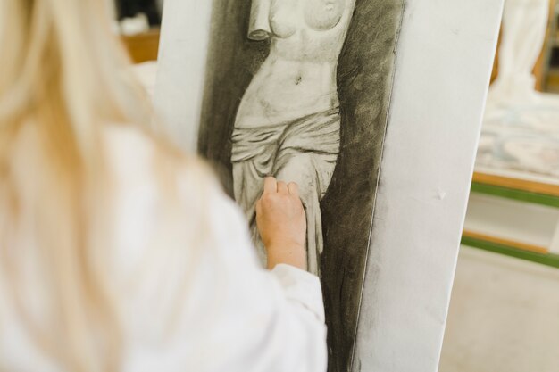 De hand die van de vrouw beeldhouwwerk op canvas schetst