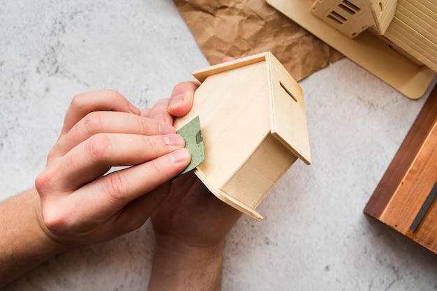 De hand die van de vrouw het houten piggybankhuis gladmaakt