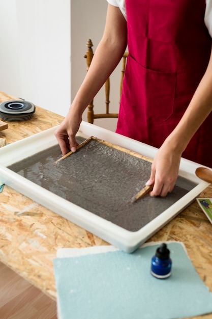 De hand die van de vrouw houten droger verwijdert uit papierpulp