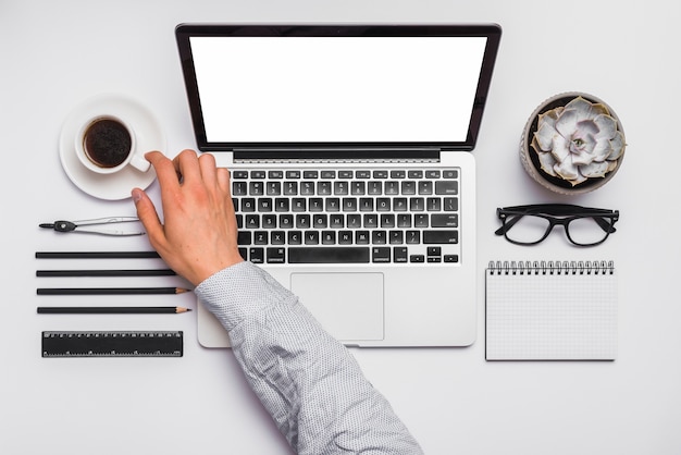 Gratis foto de hand die van de zakenman kop van koffie op bureau neemt