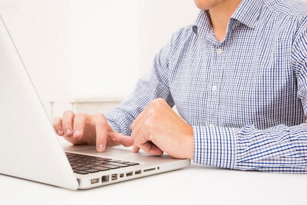 De hand die van de zakenman op laptop over witte lijst doorbladert