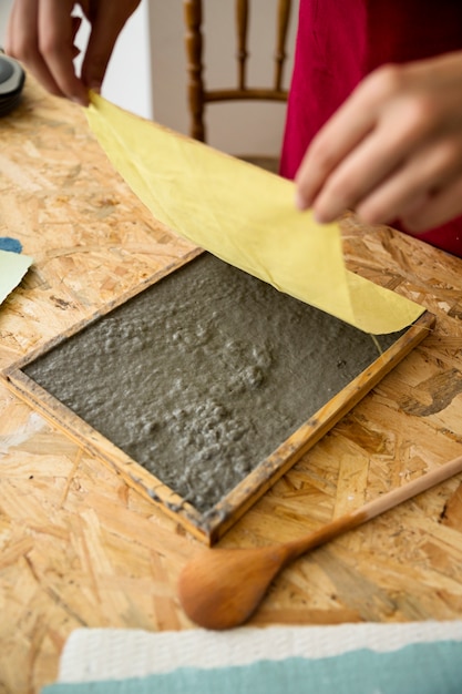 De hand die van het wijfje gele doek over document pulp plaatsen over houten bureau