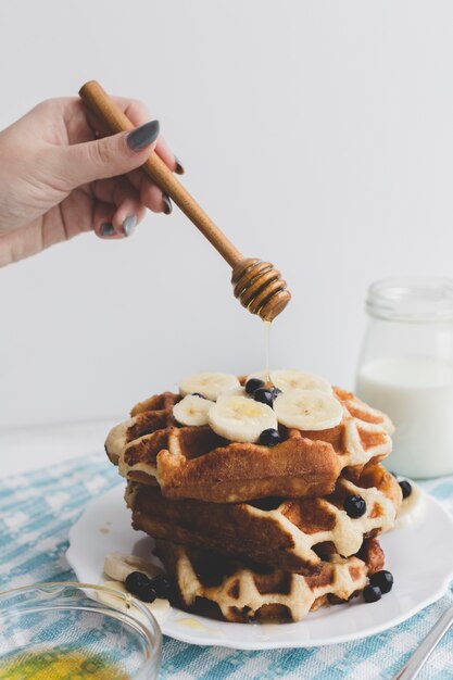 De hand gietende honing van de close-up op wafels