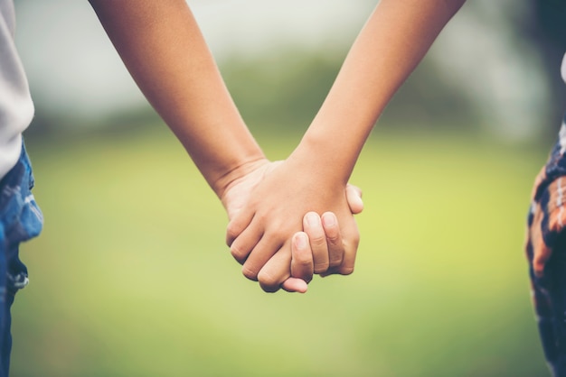 De hand van de twee meisjesvriendschap samenhoudend in het park