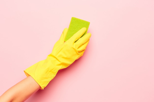 De hand van de vrouw die op een roze muur schoonmaakt. Schoonmaken of huishouden concept