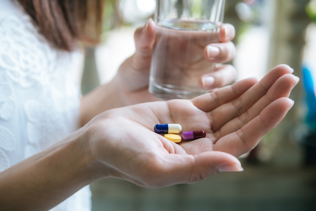 De hand van de vrouw giet de medicijnpillen uit de fles