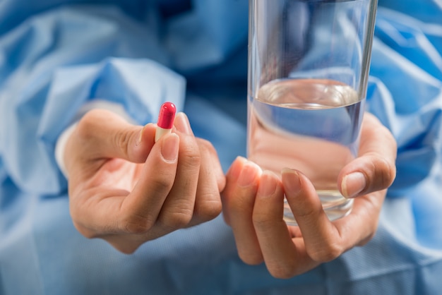 De hand van de vrouw giet de medicijnpillen uit de fles