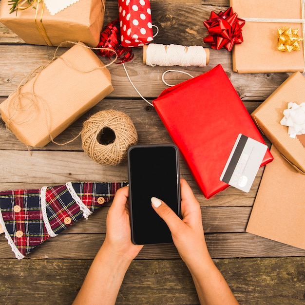 De hand van de vrouw met smartphone dichtbij plastic kaart en reeks decoratie