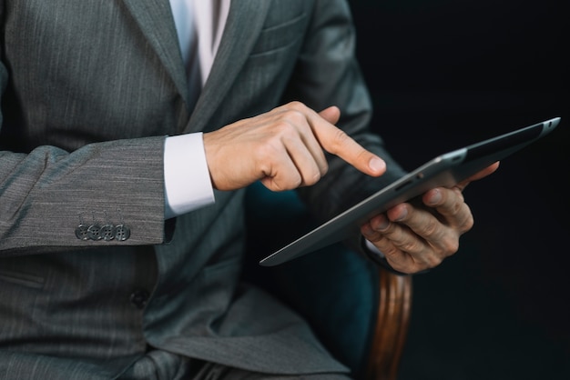 De hand van de zakenman wat betreft het digitale tabletscherm met vinger