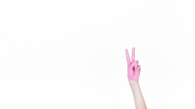 De hand van een persoon met roze verf die vredesteken toont
