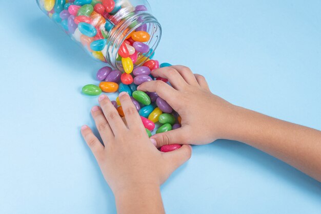 De hand van het kind met verschillende Jelly Beans op een blauwe achtergrond