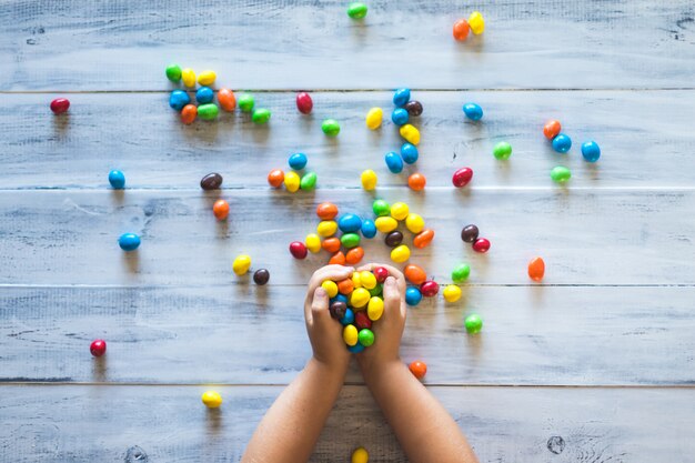 De handen die van een kind stapel van kleurrijk suikergoed houden