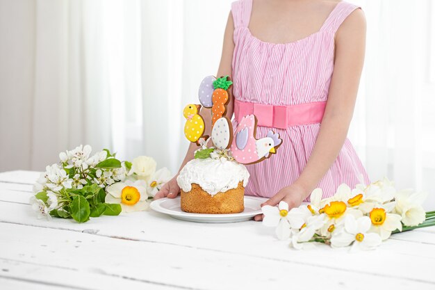 De handen van een klein meisje dat een feestelijke taart versiert. Het concept van de voorbereiding op de paasvakantie.