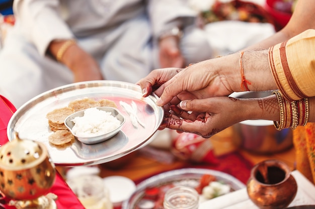 De handen van oude vrouwen houden een plaat met rijst die op Indisch huwelijk wordt voorbereid