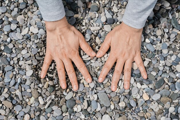 De handen van vrouwen liggen op de zeekiezelstenen Kiezelzeestrand close-up donkere ronde kiezelstenen en grijze droge kiezelstenen foto-idee van hoge kwaliteit voor scherm