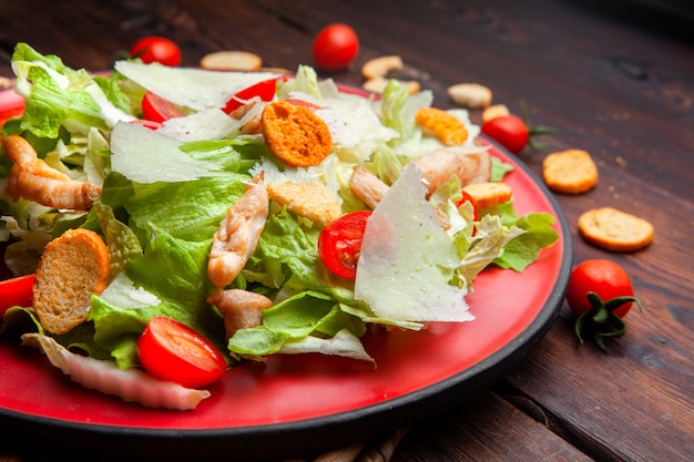 De hoge heerlijke salade van de hoekmening in een plaat op houten achtergrond. horizontaal