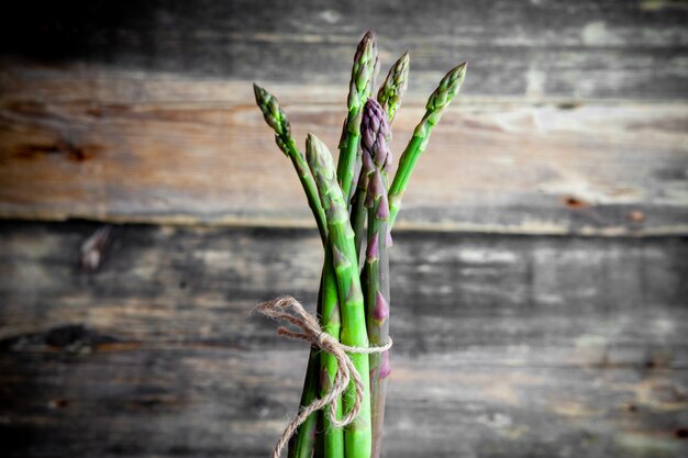 Gratis foto de hoge hoek bekijkt een bos van asperges op donkere houten achtergrond. horizontaal