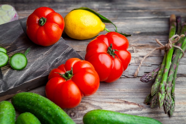 De hoge tomaten van de hoekmening in scherpe raad met gesneden komkommer, knoflook, asperge, citroen op donkere houten achtergrond. horizontaal