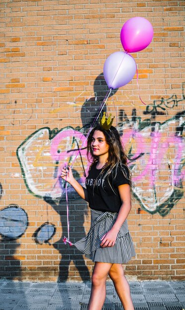 De holdingsballons van het meisje voor graffitimuur