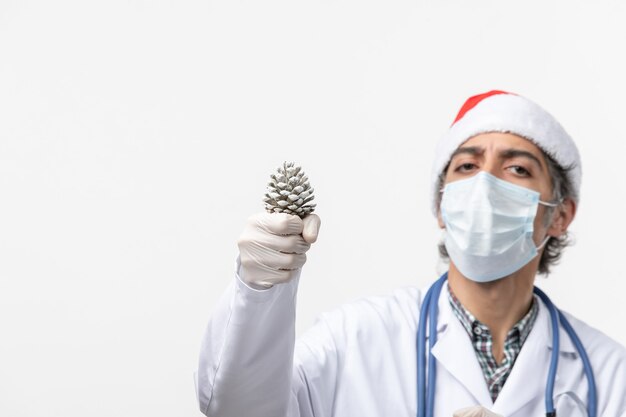 De holdingskegel van de vooraanzicht mannelijke arts op het witte virus van de muurcovid- Kerstmisgezondheid