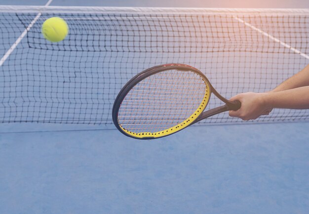 De holdingsracket van de mens ongeveer om een bal in tennisbaan te raken