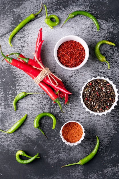 Gratis foto de hoogste peper van de meningsspaanse peper met kruiden in witte kommen op zwarte steenverticaal