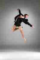 Gratis foto de jonge aantrekkelijke moderne balletdanser die op witte achtergrond springt