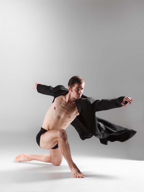 De jonge aantrekkelijke moderne balletdanser op witte muur