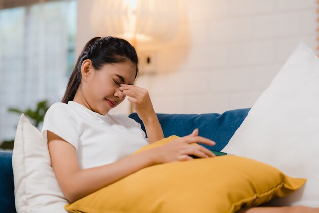 De jonge Aziatische tienervrouw die haar ogen wrijven voelt pijnlijk na het spelen van mobiele telefoon